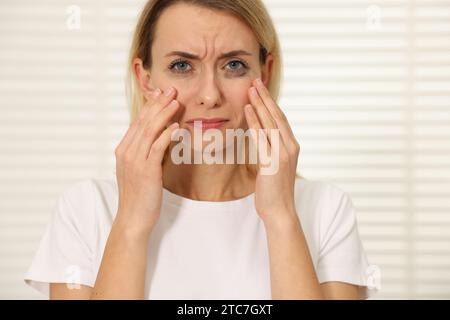 Donna triste con mascara puzzolente che piange in casa Foto Stock