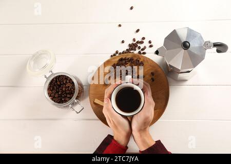 Uomo con una tazza di caffè aromatico, vista dall'alto. Moka e fagioli su un tavolo di legno bianco Foto Stock