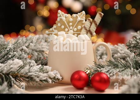 Delizioso cacao con marshmallow, bastoncini di cialda e biscotti al pan di zenzero con decorazioni natalizie su sfondo sfocato, primo piano Foto Stock