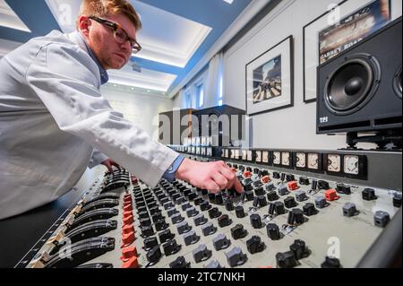 Londra, Regno Unito. 11 dicembre 2023. La EMI TG12345 Mk i Recording Console usata dai Beatles agli Abbey Road Studios per registrare il loro album "Abbey Road" Estimate su richiesta (nell'ordine di sette cifre) con, sullo sfondo, Iain Macmillan, due stampe dei Beatles su Abbey Road, 1969, stima: £ 18.000 - 20.000 e tecnici in camici bianchi Original Studio - Un'anteprima di The Sound of the Beatles: The Abbey Road Console sale a Bonhams Knightsbridge, Londra. La vendita stessa avrà luogo il 14 dicembre a Knightsbridge. Crediti: Guy Bell/Alamy Live News Foto Stock