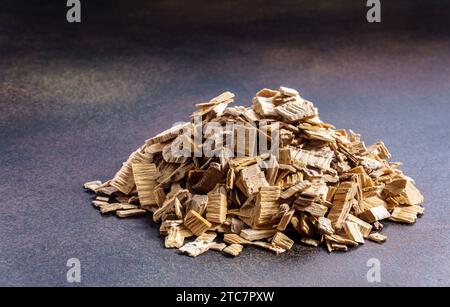 Mucchio di trucioli di legno affumicanti su sfondo scuro Foto Stock