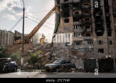 Invasione russa dell'Ucraina. Processo di demolizione di edifici residenziali. I bulldozer smontano le macerie di una casa distrutta dall'esercito russo. Foto Stock