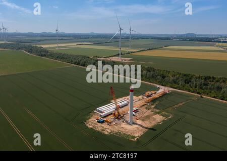 Ampia vista aerea di una turbina eolica in costruzione in mezzo a campi verdi Foto Stock