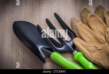 Guanti da giardinaggio in pelle con forcella e cazzuola su tavola in legno concetto agricolo Foto Stock