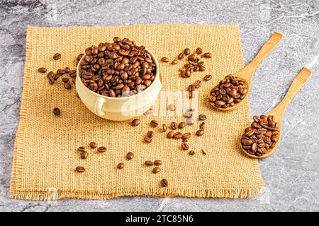 Una tovaglia di sacco piccola con una ciotola piena di chicchi di caffè. Foto Stock