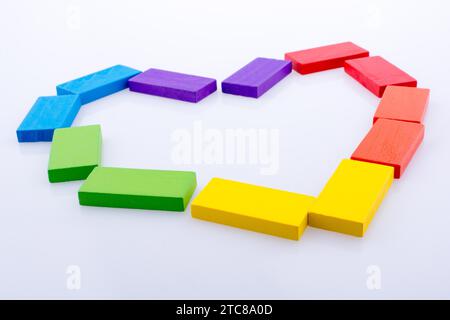 Domino colorati blocchi costituenti un cuore su sfondo bianco Foto Stock