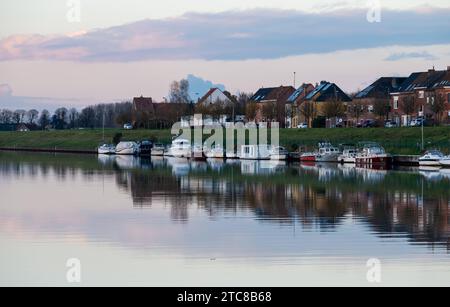 Grimbergen, regione del Brabante fiammingo, Belgio, 28 novembre 2023 - case residenziali in fila e barche che riflettono nell'acqua del canale al crepuscolo credito: Imago/Alamy Live News Foto Stock