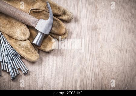 Spazio copia dei guanti di sicurezza in pelle e dei chiodi lunghi in acciaio su fondo in legno Foto Stock