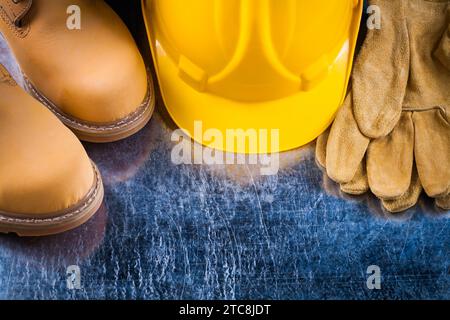 Stivali antinfortunistici guanti in pelle e casco da costruzione su superficie metallica graffiata concetto di costruzione orizzontale Foto Stock