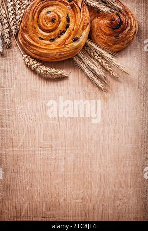 Spighe di grano maturo ricco di uva passa al forno panini su legno di legno di legno di oaken cibo e bevande concetto Foto Stock