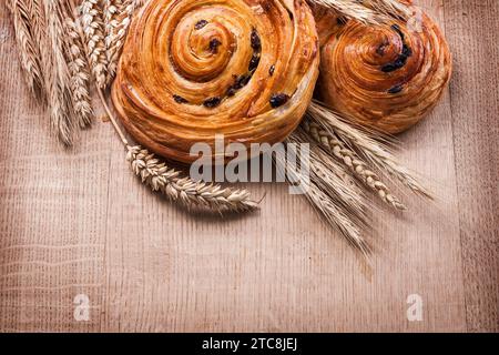 Involtini al forno con uva passa maturi alle orecchie di grano su tavola di legno di legno e bevande Foto Stock