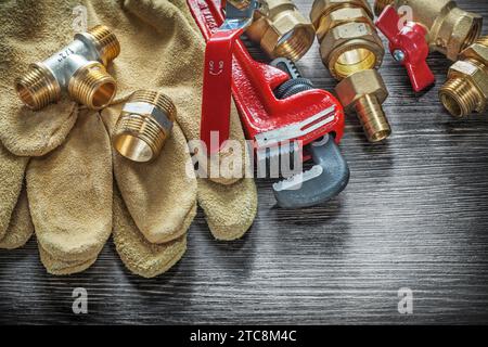 Raccordi per giratubi guanti di sicurezza valvole acqua su tavola di legno Foto Stock