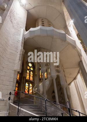 La luce inonda attraverso le vetrate colorate di una scala a chiocciola nel design della basilica de la Sagrada Familia Foto Stock