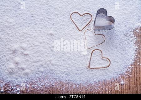 Biscotti copyspace organizzati modellano sotto forma di cuore su farina e tavola di legno concetto di cibo e bevande Foto Stock