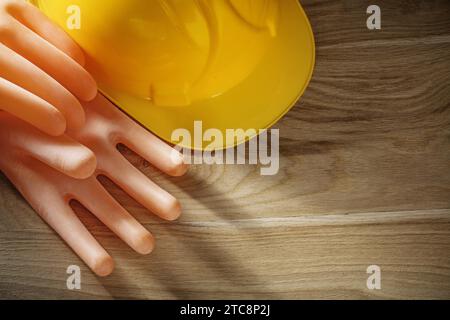 Casco da costruzione con guanti dielettrici su tavola di legno Foto Stock