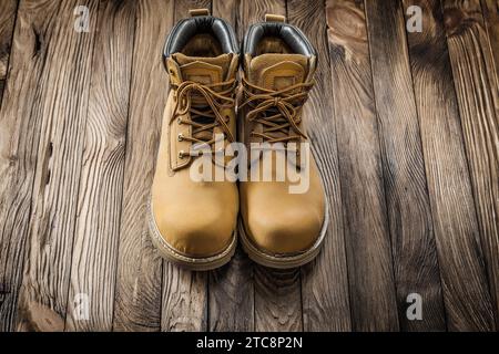 Gli utensili da costruzione sega indossano stivali da lavoro in pelle su tavole in legno vintage Foto Stock