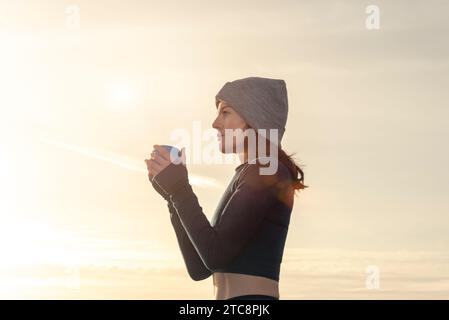 Donna sportiva con un drink da asporto all'aperto dopo l'esercizio mattutino Foto Stock