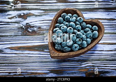 Huckleberries in una ciotola di legno su una tavola di legno Foto Stock