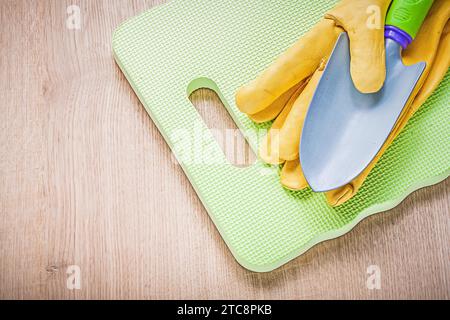 Guanti di sicurezza in pelle tappetino per ginocchia da giardino a vanga in metallo su tavola di legno concetto agricolo Foto Stock