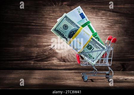 Pacchetti di dollari ed euro in un carrello per la spesa in legno d'epoca Foto Stock