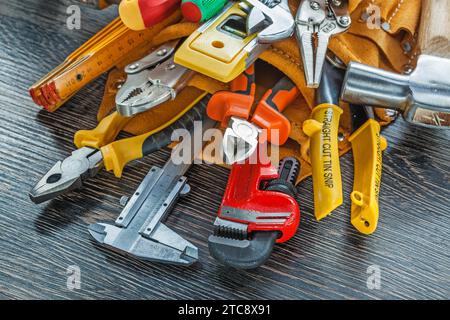 Utensili per la costruzione di cinture portautensili in pelle su uno sfondo in legno Foto Stock