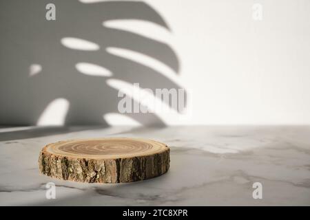 Podio in legno con ombra di foglie monstera per la presentazione di cosmetici naturali o prodotti Foto Stock