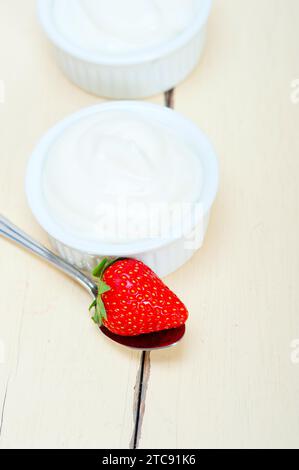 Yogurt greco biologico e fragola su tavola di legno rustico bianco Foto Stock