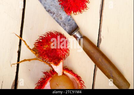 Frutti di rambutan tropicali freschi su un tavolo in legno rustico Foto Stock