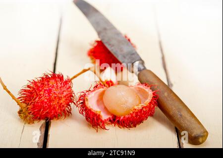 Frutti di rambutan tropicali freschi su un tavolo in legno rustico Foto Stock