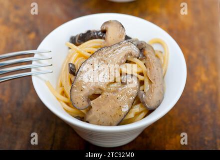 Italiano gli spaghetti e i funghi selvatici freschi sulla tavola in legno rustico Foto Stock