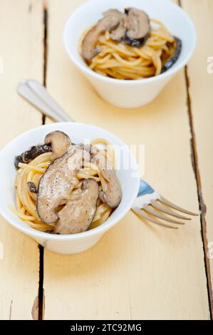 Italiano gli spaghetti e i funghi selvatici freschi sulla tavola in legno rustico Foto Stock