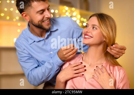 Un uomo che con affetto regala una collana a una donna felice Foto Stock