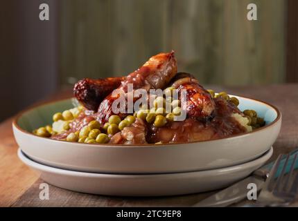 Salsicce del Cumberland con purè di patate, piselli da giardino e un ricco sugo di cipolla. Foto Stock