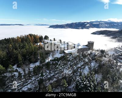 Vista aerea di un maestoso castello circondato da una coltre di montagne innevate Foto Stock