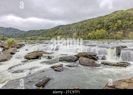 Un paesaggio mozzafiato caratterizzato da una cascata che cade su rocce e alberi su una riva del fiume Foto Stock
