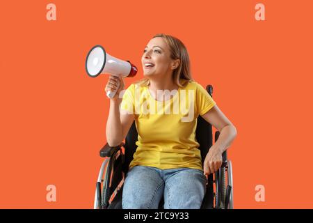 Donna matura in sedia a rotelle che urla al megafono su sfondo rosso Foto Stock