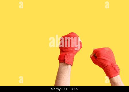 Mani femminili con bende da boxe su sfondo giallo Foto Stock