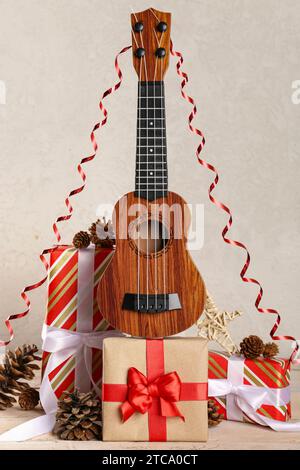 Composizione con ukulele, regali di Natale e decorazioni su un tavolo di legno chiaro Foto Stock