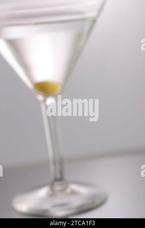 Foto da sogno di un Martini mixato astratto con tre cornici di olive sullo sfondo dello studio Foto Stock