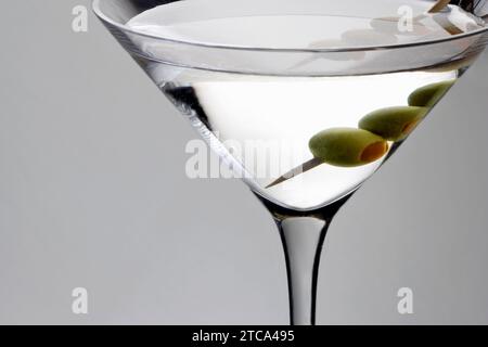 Martini bevanda miscelata con olio di oliva guarnite su uno sfondo grigio chiaro con la riflessione Foto Stock