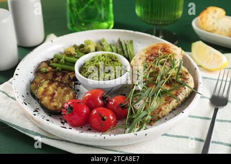 Pollo gustoso, verdure con dragoncello e pesto serviti al tavolo, primo piano Foto Stock