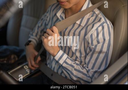 Immagine ravvicinata di un uomo che fissa la cintura di sicurezza alla guida di un'auto. La sicurezza prima di tutto, le persone e il concetto di veicolo Foto Stock