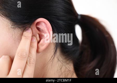 Una donna che soffre di perdita dell'udito preme le orecchie con le dita Foto Stock