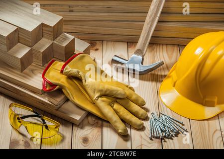 Utensili da carpentiere guanti casco martello chiodi occhiali di sicurezza su fondo legno Foto Stock