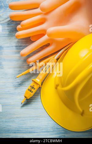 Tester elettrico guanti dielettrici casco da costruzione su tavola di legno concetto di elettricità Foto Stock