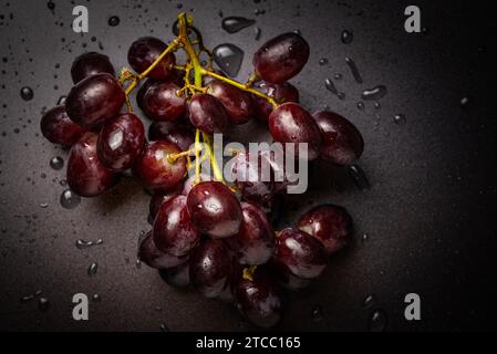 Primo piano di uve rosse su sfondo nero con spazio di copia. Gocce d'acqua, concetto di lavaggio Foto Stock