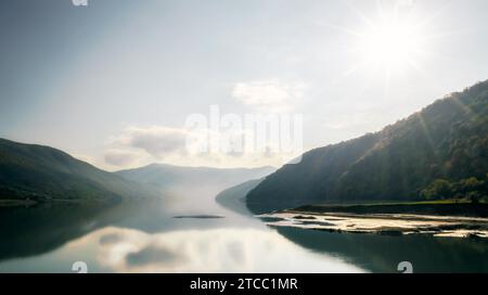 Paesaggio di montagna autunnale con foresta verde e lago sullo sfondo dei raggi del sole e del cielo e delle nuvole in Georgia Foto Stock