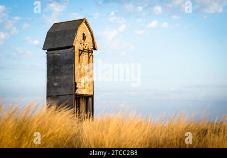Vecchia e insolita casa in un campo su uno sfondo di cielo blu e nuvole Foto Stock