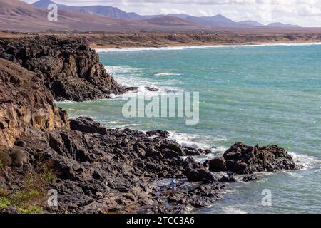 Vista panoramica sulla costa di El Cotillo sull'isola canaria di Fuerteventura, Spagna con rocce laviche e catena montuosa sullo sfondo Foto Stock