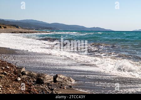 Vista panoramica sulla costa con spiaggia di ciottoli e onde d'acqua sul lato ovest dell'isola greca di Rodi tra Kamiros e Mandriko Foto Stock
